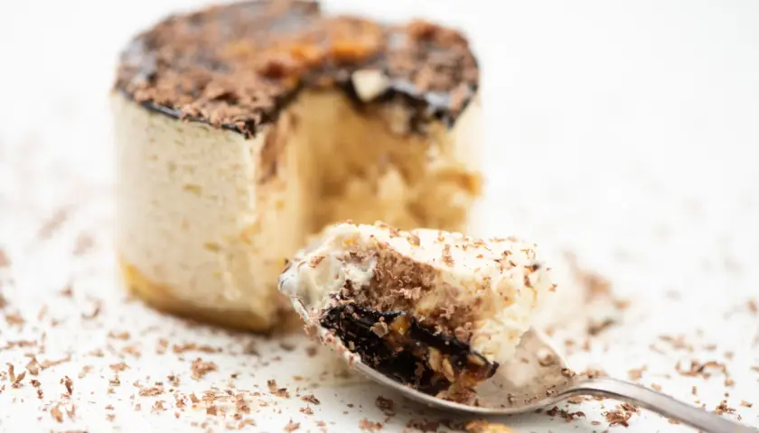 Un cucchiaino raccoglie un pezzo di delizioso parfait, con strati di crema e cioccolato, cos'è questa bontà?