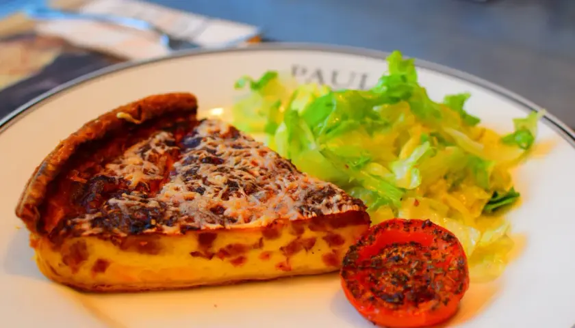 Kawałek quiche lorraine, sałatka i pieczony pomidor – klasyka kuchni francuskiej.