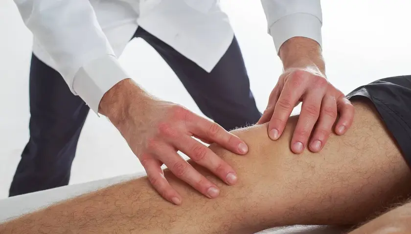 Terapeuta wykonuje delikatne ruchy na nodze pacjenta, co ilustruje, na czym polega terapia Bowen'a.