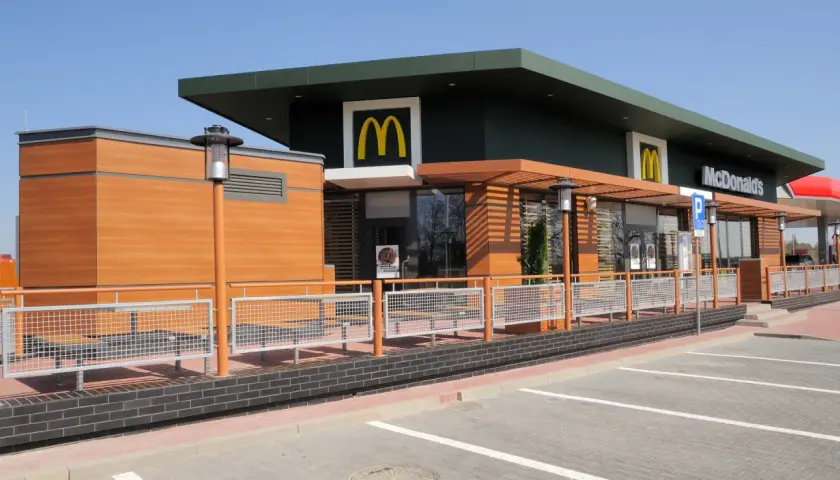 Nowoczesny McDonald's z drewnianymi elementami i dużymi oknami. Idealne miejsce na szybki posiłek, może nawet na słynne krewetki McDonald's, jeśli będą dostępne.