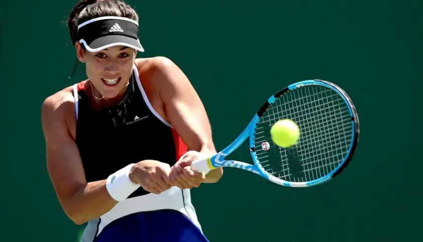 Garbine Muguruza z determinacją uderza piłkę rakietą podczas meczu tenisowego.