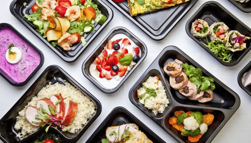 Różnorodne dania z cateringu dietetycznego Augustów: sałatka z krewetkami, jogurt z owocami, ryż z kurczakiem, warzywa i mięso.