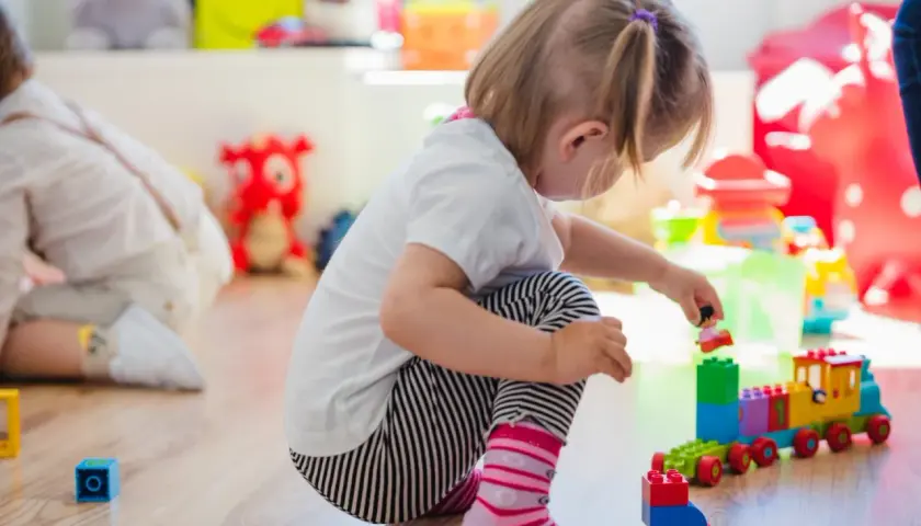 Niña jugando con bloques, concentrada en su mundo, un ejemplo de egocentrismo infantil.