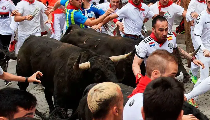 Hombres corren junto a toros negros de ganadería Guadaira.
