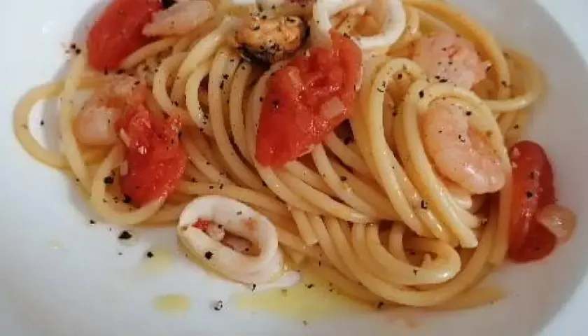 Pyszne spaghetti z owocami morza: krewetki, małże i kalmary w sosie pomidorowym z ziołami.