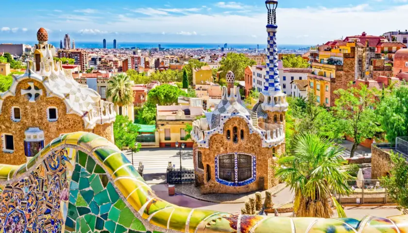Kolorowa mozaika i budynki w Parku Güell w Barcelonie z widokiem na miasto.
