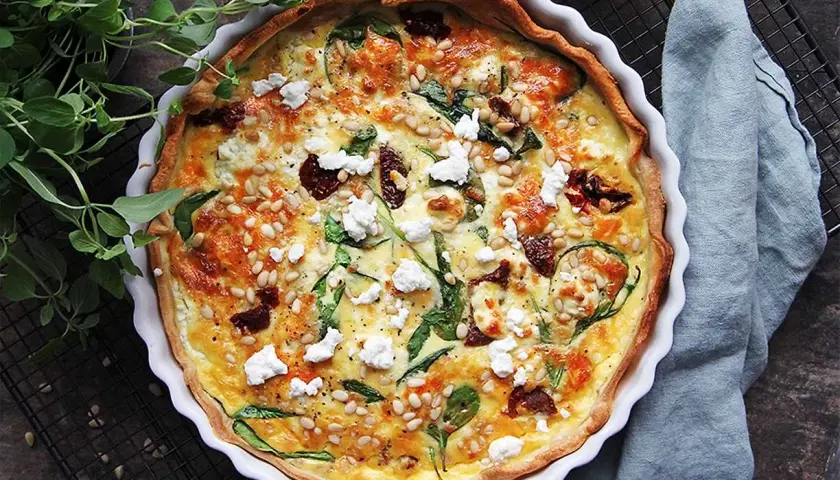 En gyllene, smakrik vegetarisk paj med spenat, soltorkade tomater och pinjenötter. Perfekt för en mysig middag.