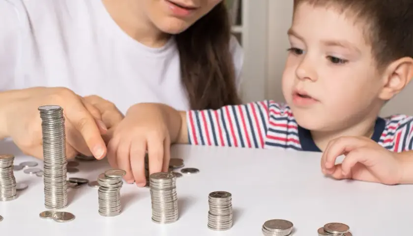 Mama z synkiem liczą monety, planując wydatki na dziecko. Zasiłek opiekuńczy na dziecko może pomóc w takich sytuacjach.