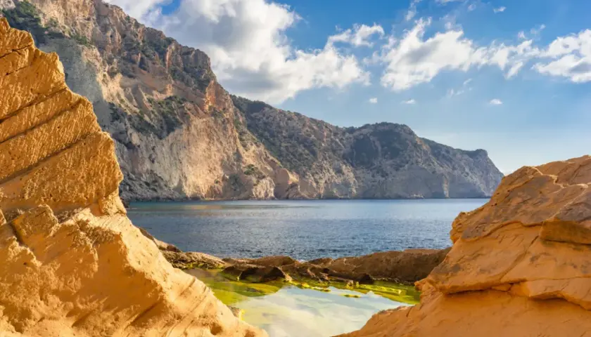 Acantilados dorados y mar azul en Ibiza, un rincón que evoca la magia de Atlantis Ibiza.