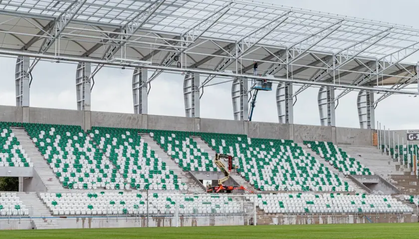 Stadion Radomiaka w budowie. Zielono-białe trybuny czekają na kibiców, a pracownicy montują dach.
