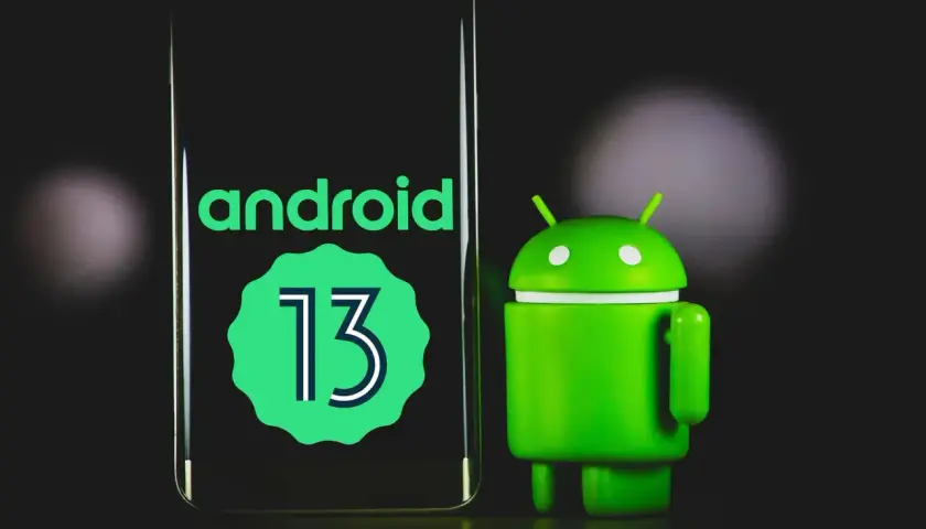 Zielony robot Android obok ekranu z napisem "android 13".