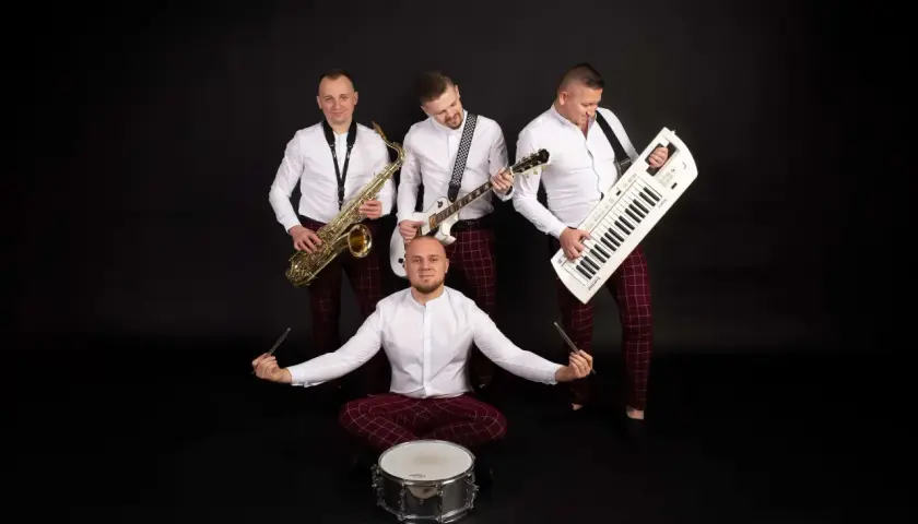Zespół muzyczny grupa speed: saksofonista, gitarzysta, klawiszowiec i perkusista w białych koszulach i bordowych spodniach w kratę.