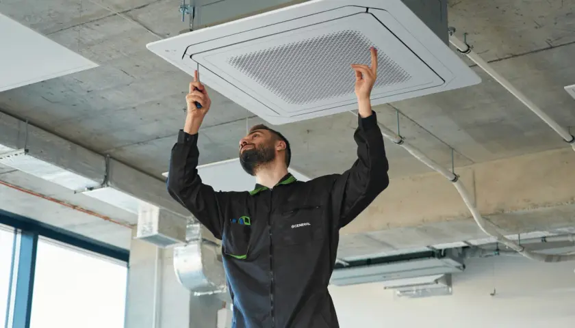 Técnico instalando equipos de climatización en el techo.