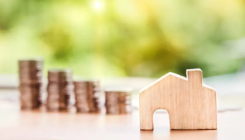 Une petite maison en bois et des piles de pièces de monnaie suggèrent un coup de pouce pour quel groupe : les investisseurs immobiliers.