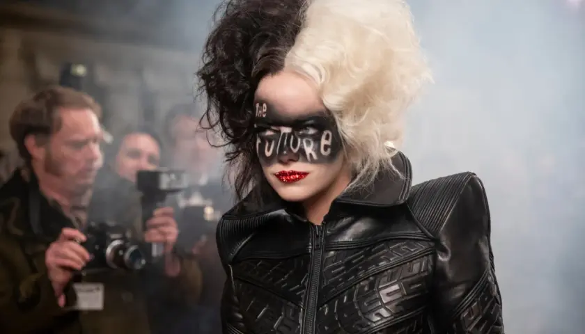 Cruella med "The Future" skrivet i ansiktet, omgiven av fotografer.