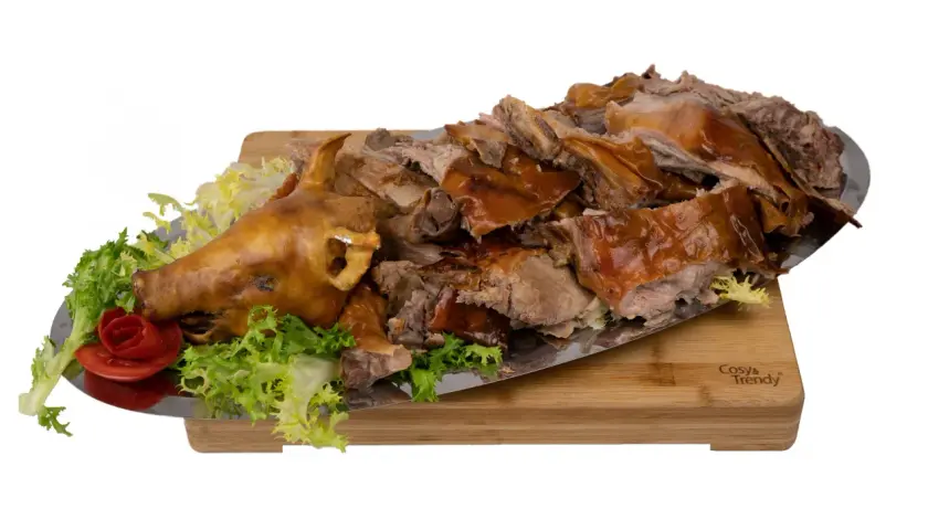 Un cochon de lait entier, rôti à la perfection, est servi sur un plateau avec de la laitue et une rose en tomate. La cuisson du cochon de lait est impressionnante.