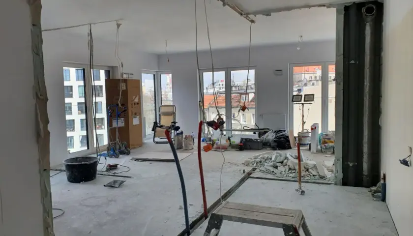 Budowa mieszkania deweloperskiego: widok wnętrza w trakcie prac remontowych, materiały budowlane, okna.