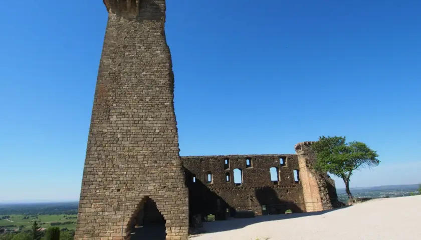 Ruinen der Burg von Châteauneuf-du-Pape, ein imposanter Turm und zerfallene Mauern unter blauem Himmel.