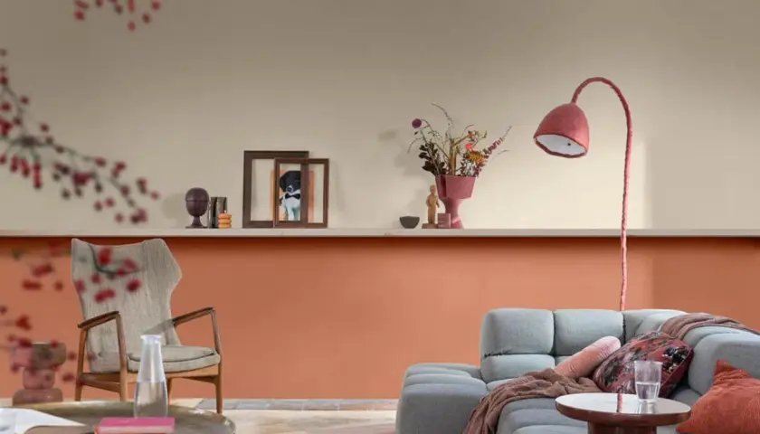 Un accogliente soggiorno con una parete scala bicolore, arricchito da un divano grigio, una poltrona vintage e decorazioni.