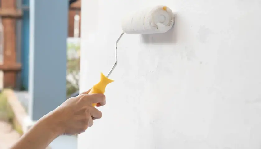 Mano pinta pared interior con rodillo. ¿Qué pasa si pinto con pintura de exterior en interior?