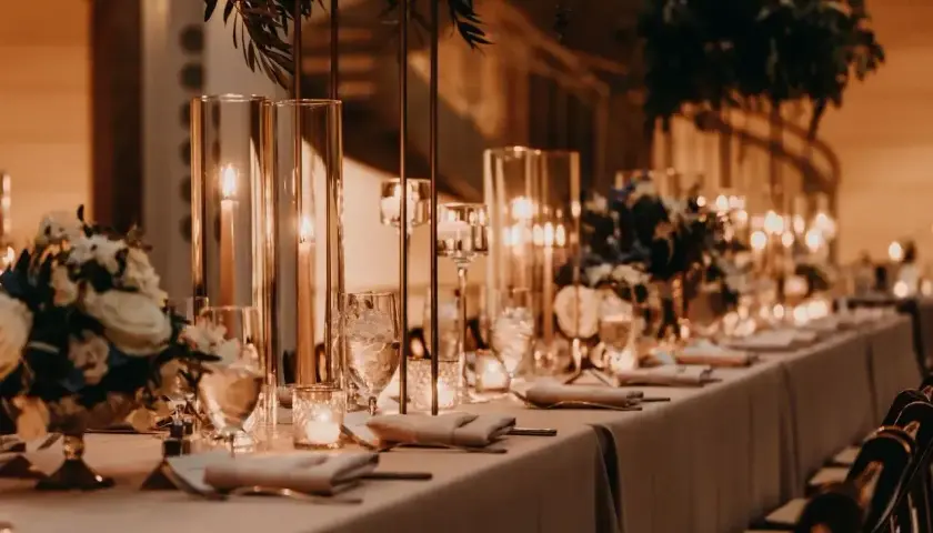 Elegancka sala weselna z długim stołem, świecami i kwiatami. Zastanawiasz się, ile kosztuje sala weselna?