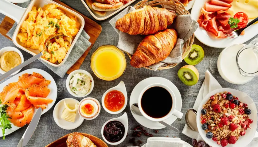 Un festin pour un brunch mariage : œufs brouillés, saumon fumé, croissants, fruits, café et granola.
