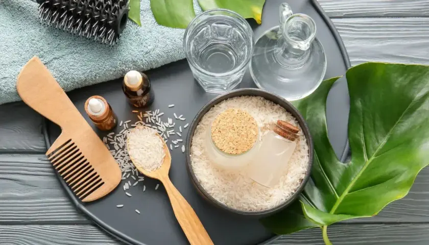 Ingredientes para el agua de arroz para el pelo: arroz, aceites, peine de madera, cepillo y toalla.
