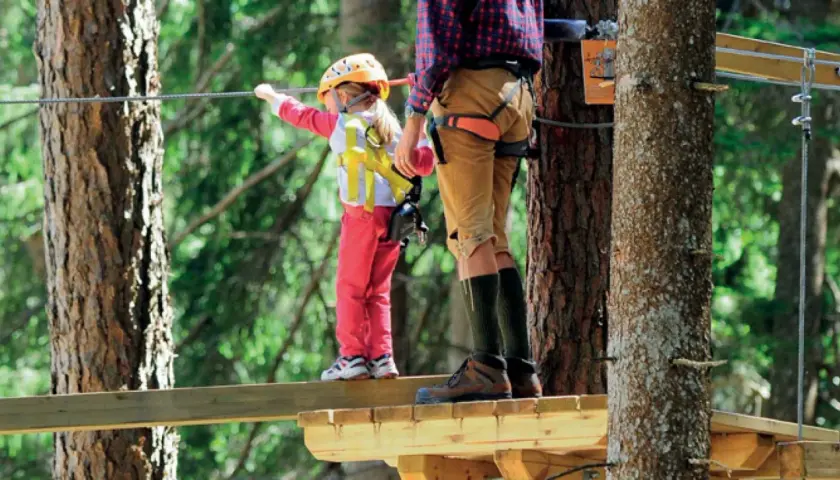 Un bambino e un adulto su un percorso avventura. Un perfetto weekend con bambini nel Nord Italia, tra alberi e adrenalina.