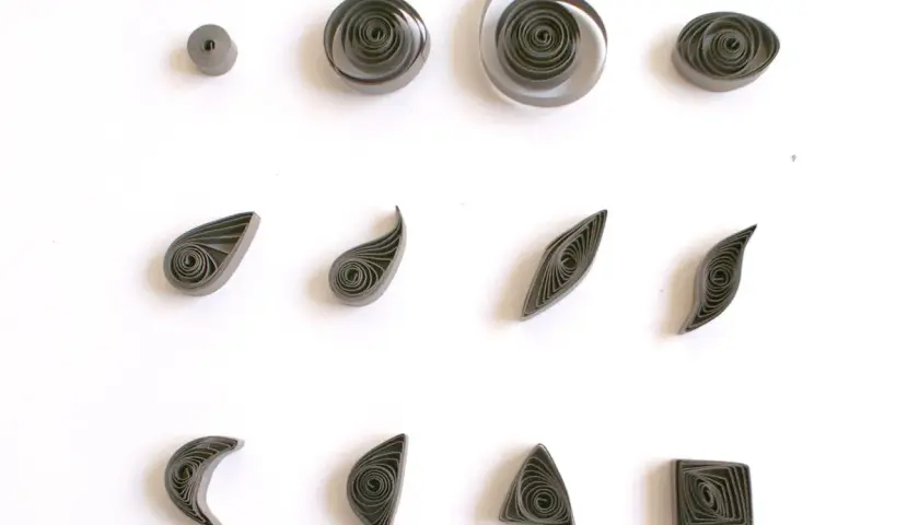 Różne kształty z papieru, pokazujące, quilling co to jest. Kółka, łezki, listki, księżyce, trójkąty i kwadraty.