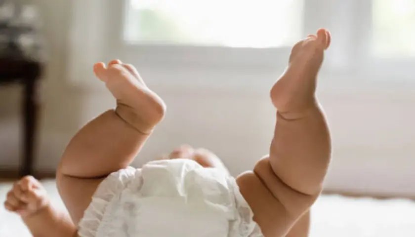 Gambe paffute di un neonato con pannolino, un tenero culo rosso pronto per un cambio.