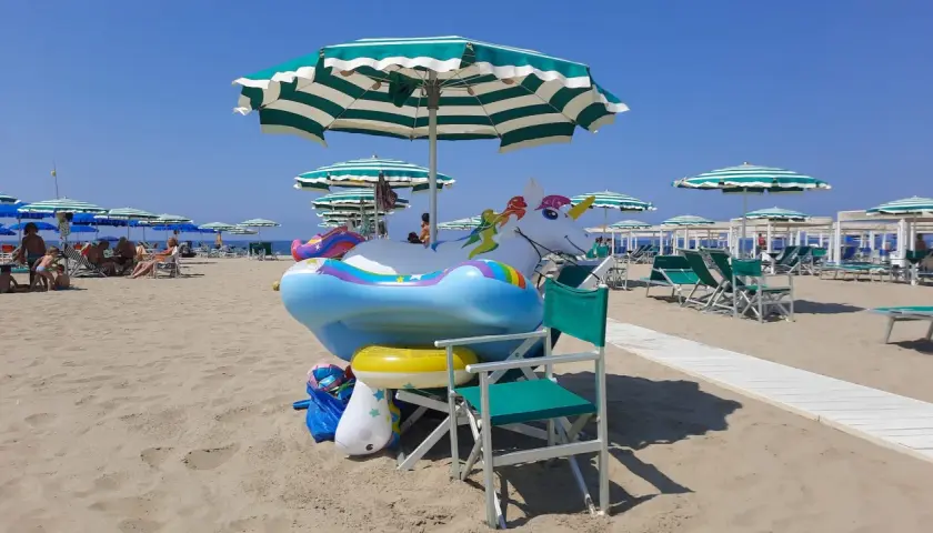 Spiaggia di Viareggio con gonfiabili a forma di unicorno e arcobaleno, pronti per i bambini.