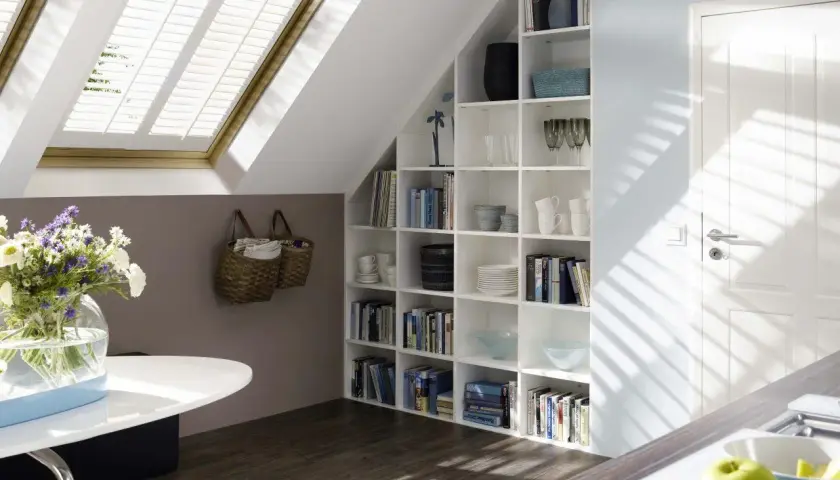 Una libreria in mansarda, piena di libri e oggetti decorativi, si integra perfettamente con l'ambiente.