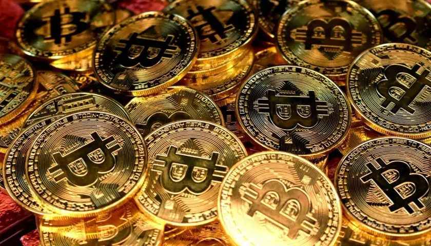 Złote monety z symbolem Bitcoina, symbolizujące jego wartość.