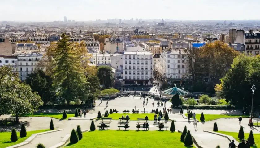 Blick über das Montmartre Viertel in Paris. Menschen genießen den sonnigen Tag im Park mit Blick auf die Stadt.
