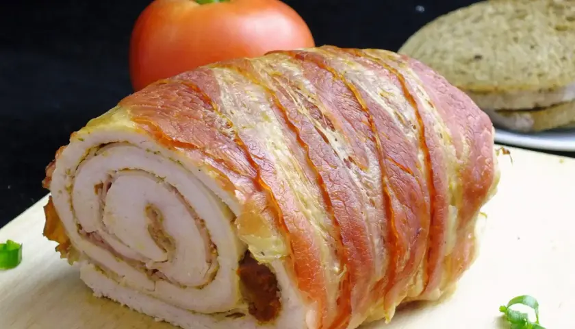 Roladki z indyka z boczkiem, soczyste i aromatyczne, gotowe do podania z pomidorem i chlebem.
