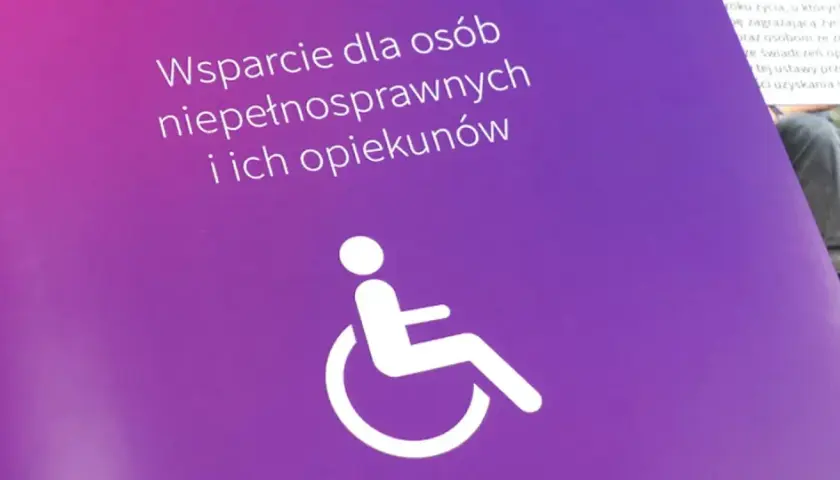 Fioletowy baner z napisem "Wsparcie dla osób niepełnosprawnych i ich opiekunów" oraz symbolem wózka inwalidzkiego.