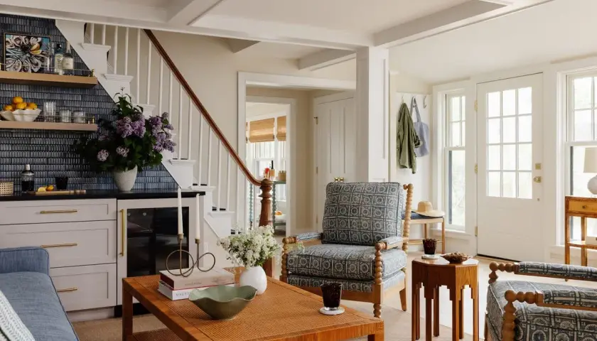A living room showcasing diverse furniture styles, from a blue sofa and patterned armchairs to a rattan coffee table and a wooden side table.
