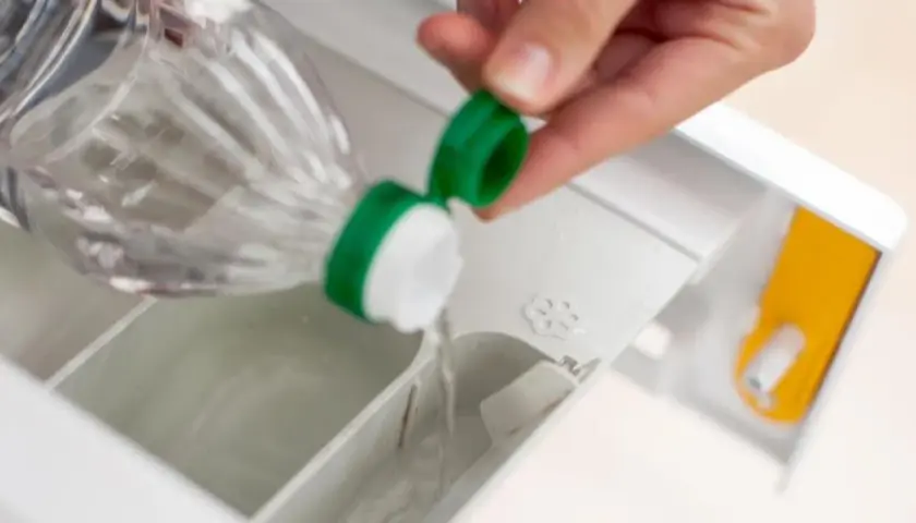 Essig wird in das Waschmittelfach der Waschmaschine gegossen, um Wäsche aufzufrischen und Kalk zu entfernen.