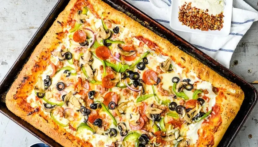 Pyszny przepis na pizzę z serem, pepperoni, pieczarkami, papryką i oliwkami. Idealna na rodzinny obiad.