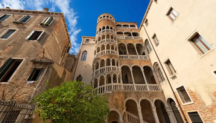 Le célèbre escalier en colimaçon du Bovolo à Venise, une merveille architecturale médiévale, se dresse fièrement sous un ciel bleu éclatant.
