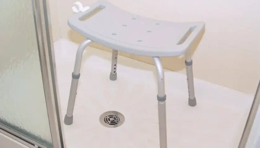 Ein Duschhocker, eine wichtige Duschhilfe für Senioren, steht in einer Duschkabine.