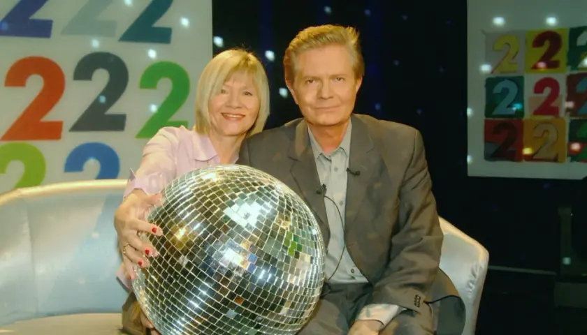 Krzysztof Szewczyk z partnerką i kulą dyskotekową na tle cyfr 222.