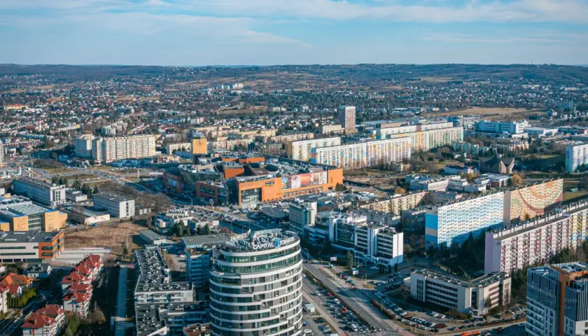 Widok na Rzeszów z lotu ptaka. Widać nowoczesne budynki, centrum handlowe i osiedla mieszkaniowe. Ceny mieszkań Rzeszów są tu widoczne w kontekście rozwoju miasta.