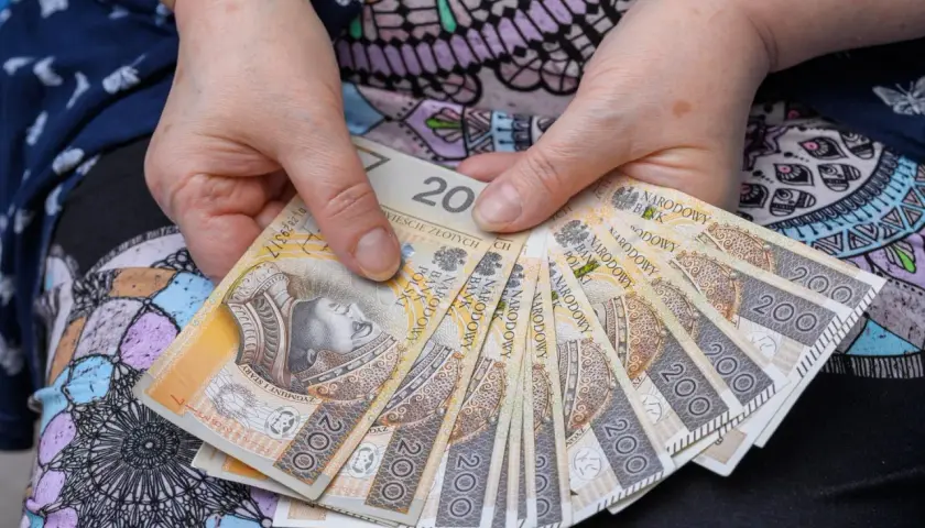 Dłonie trzymające banknoty 200 zł. Może to być zapowiedź wypłaty bonu senioralnego 2026.