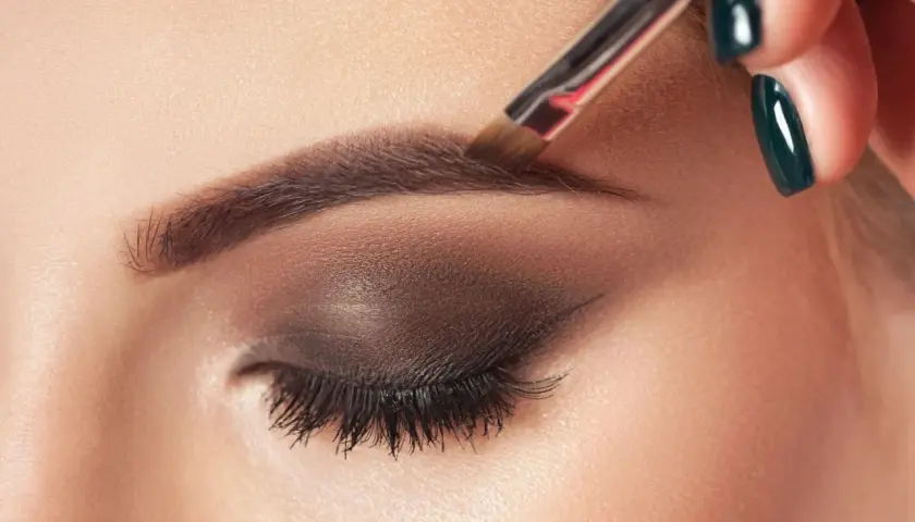 Aplicando el toque final al maquillaje de cejas con un pincel.