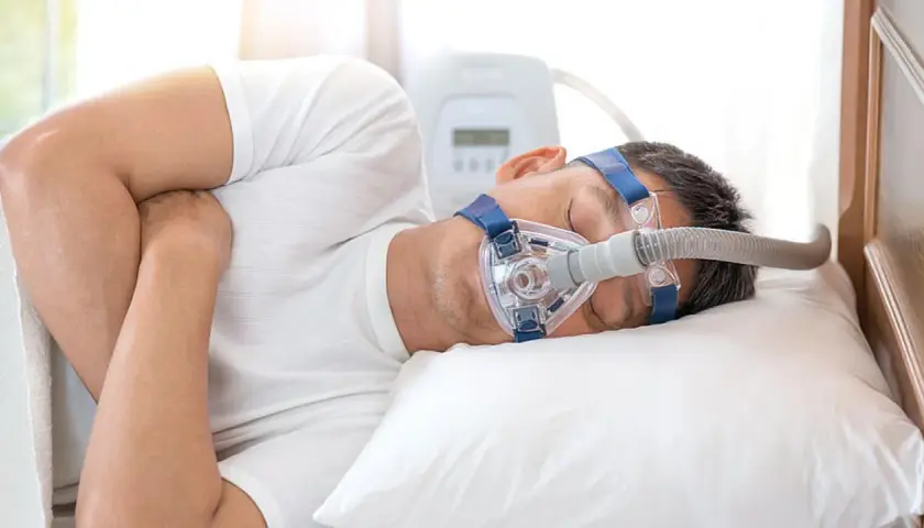 Mann schläft mit CPAP-Maske, um Atemaussetzer am Tag zu behandeln.