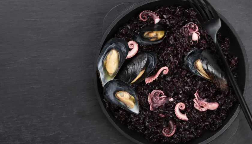 Arroz negro con mejillones y pulpo tierno, un plato de mariscos oscuro y delicioso.