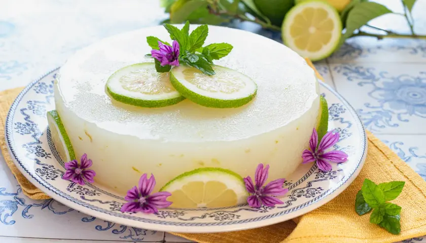 Delizioso gelo di limone, decorato con fette di limone, fiori viola e foglie di menta. Fresco e invitante.