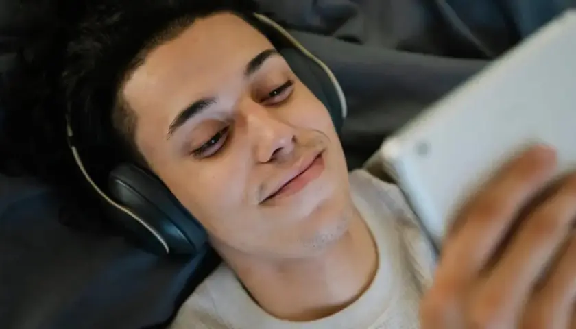 Giovane con cuffie e tablet, forse in un momento di solitudine, tra autoerotismo e depressione.