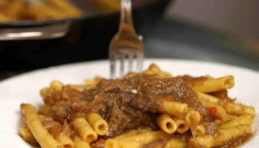 Un piatto invitante di ziti alla genovese, con la pasta condita da un ricco ragù di carne e cipolle.